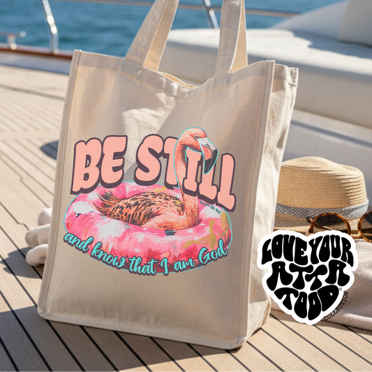Jumbo tote bag the features a pink flamingo float that say Be still and know that I am God