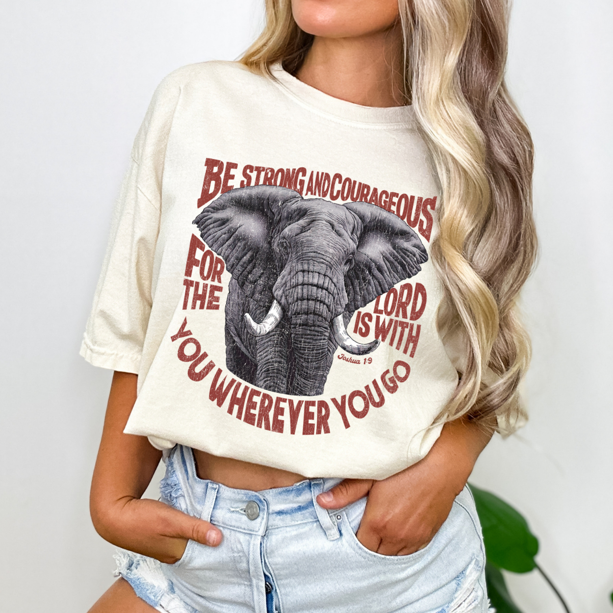 Person wearing a white t-shirt with an elephant graphic and text.  Be strong and courageous for the lord is with you