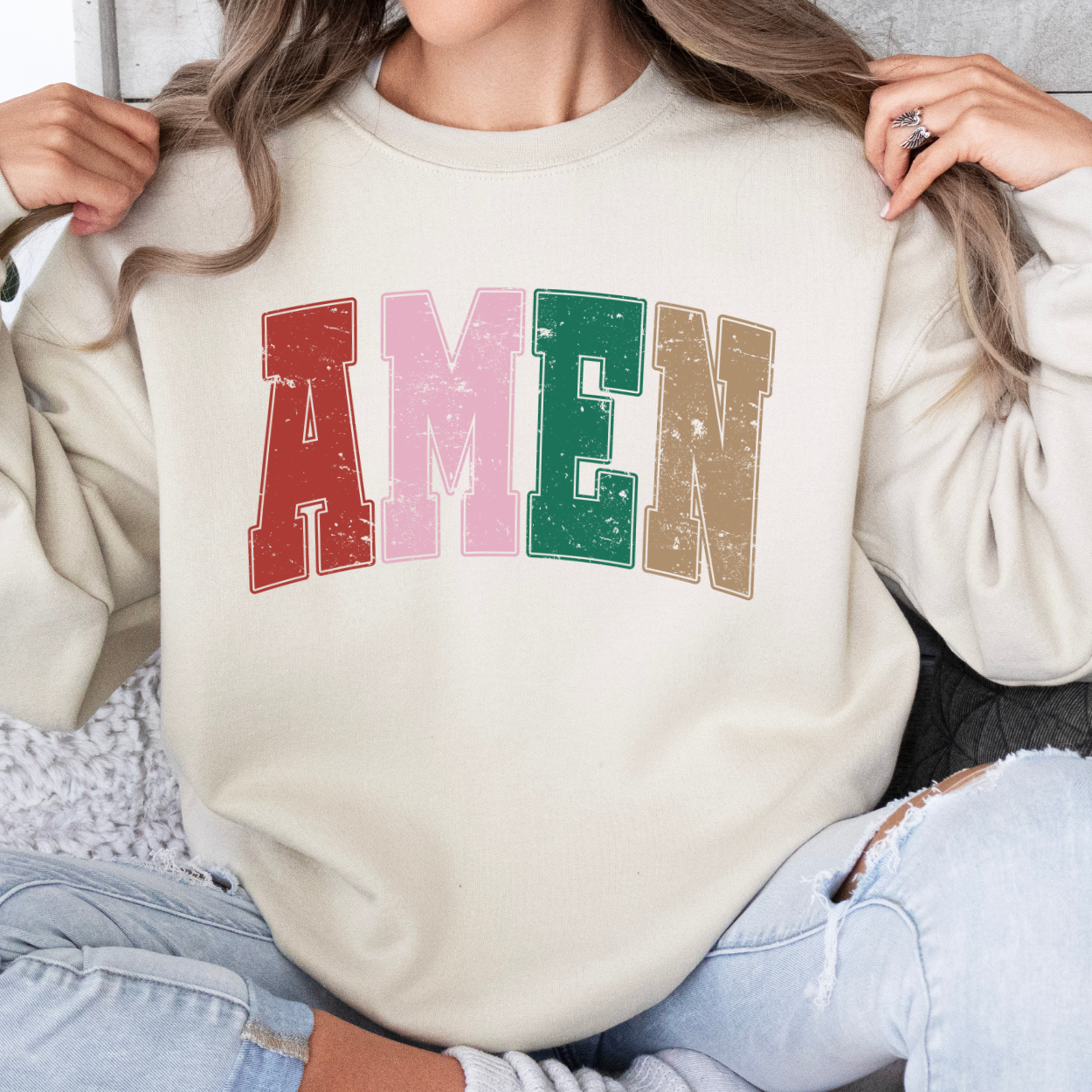 Person wearing a sand color sweatshirt with the word AMEN across the chest in red, green, pink and tan