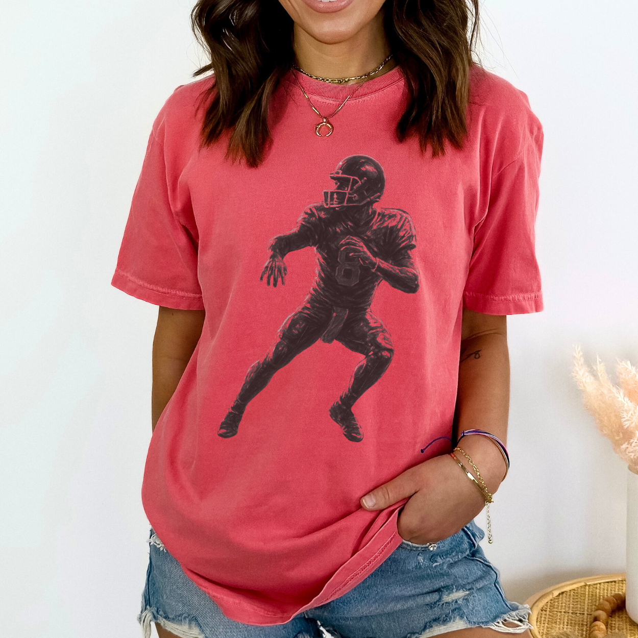 Person wearing a red t-shirt with a black silhouette of a football player on a white background