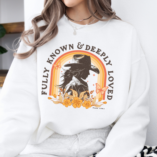 Fully known and deeply loved psalm 139:1 on a white sweatshirt.  Features a silhouette of a cowgirl with orange flowers and butterfly
