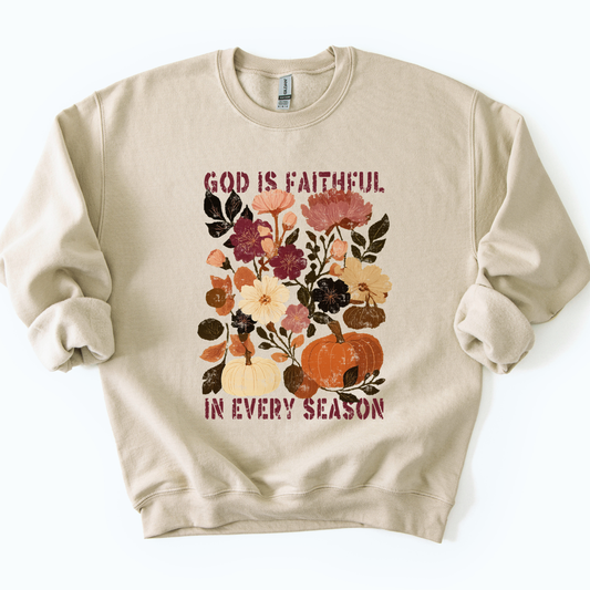 Beige sweatshirt with floral and pumpkin design and text 'God is faithful in every season' on a white background