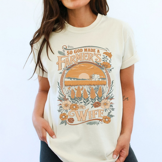 Person wearing a t-shirt with a graphic design and text on a white background.  So God made a Farmer's Wife.  Corn field with tractor as a graphic