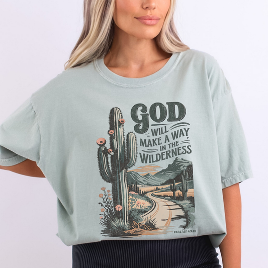 Person wearing a light blue t-shirt with a cactus graphic and text on a white background.  God will make a way in the wilderness Isaiah 43:19