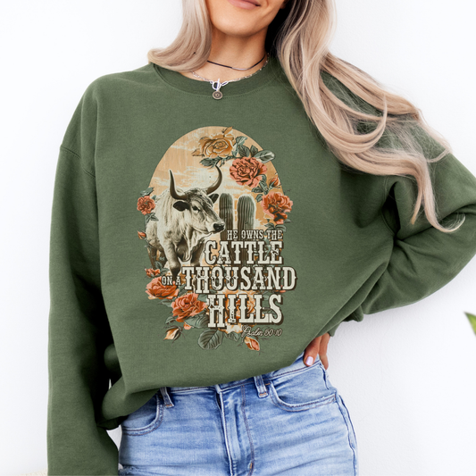He owns the cattle on a thousand hills Psalm 50:10 military green sweatshirt.  Graphic is a long horn cow with cactus and roses