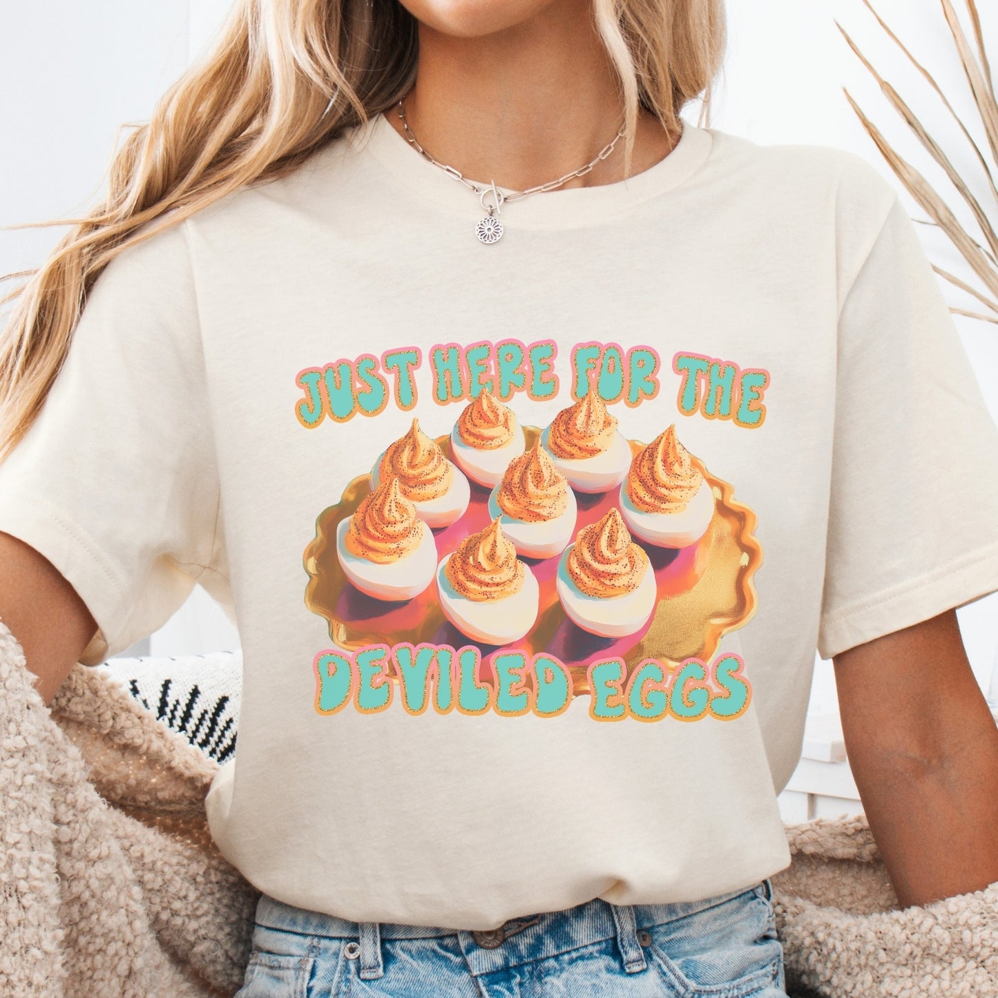 Person wearing a white t-shirt with a graphic of deviled eggs and text.