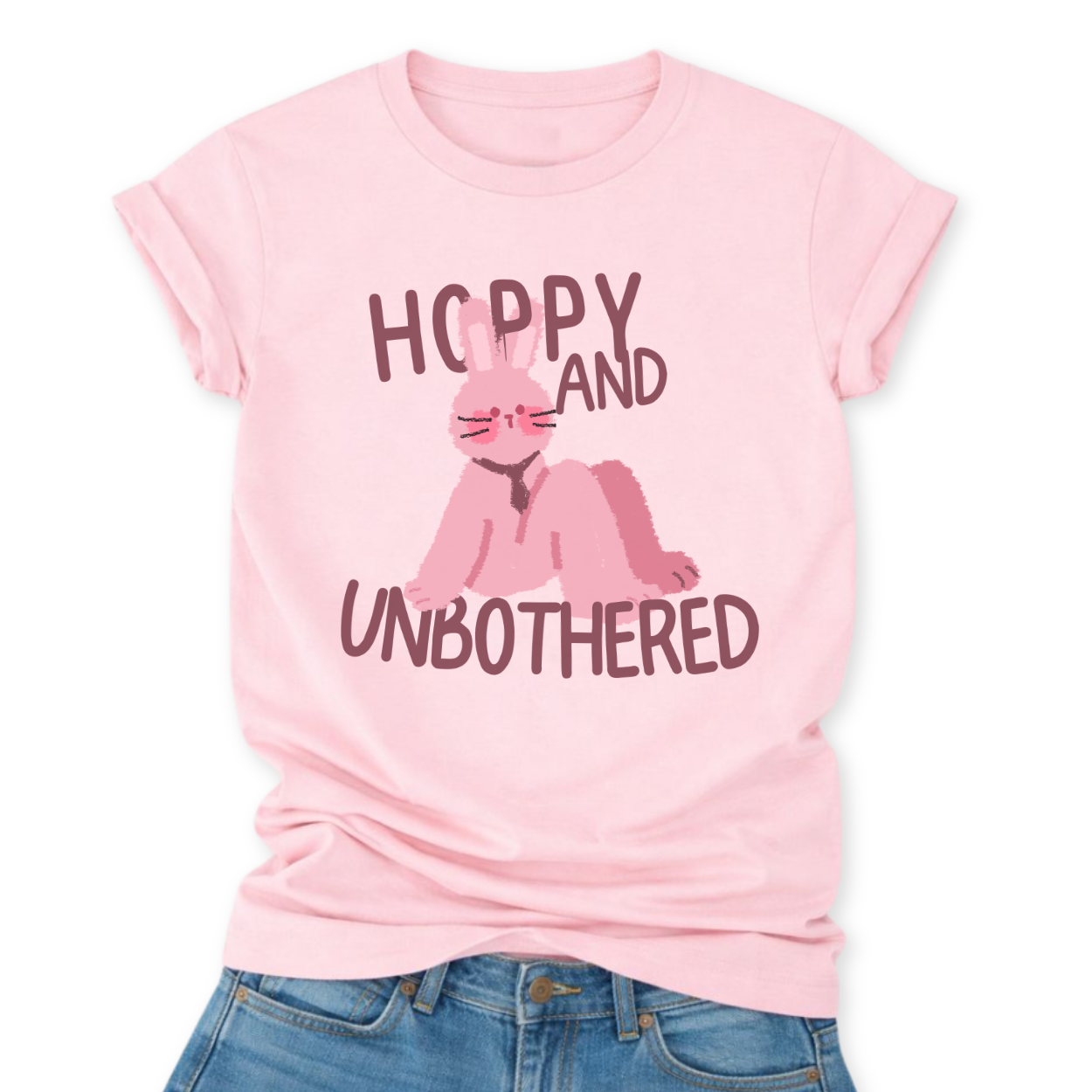 Heather Pink Playful Easter graphic on a Bella Canvas t-shirt. The design features a relaxed pink bunny illustration paired with the bold phrase “Hoppy and Unbothered” in modern, oversized lettering. The artwork blends trendy humor with soft seasonal styling, making it a fun spring statement piece.