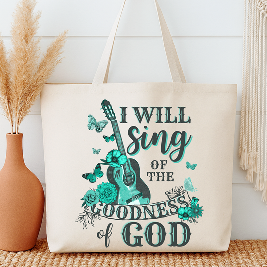 Tote bag with 'I Will Sing of the Goodness of God' text and guitar design next to a vase and decorative items.