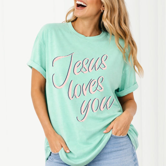 Woman wearing a mint green t-shirt with 'Jesus loves you' text on a white background