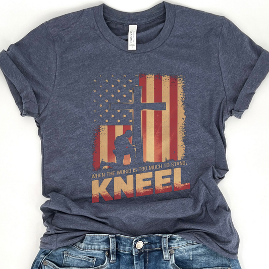 Blue t-shirt with American flag and silhouette graphic on a white background.  When the world is too much to stand, Kneel