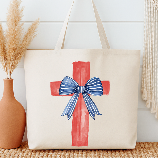 Beige tote bag with red cross and blue bow design next to a vase with dried plants.
