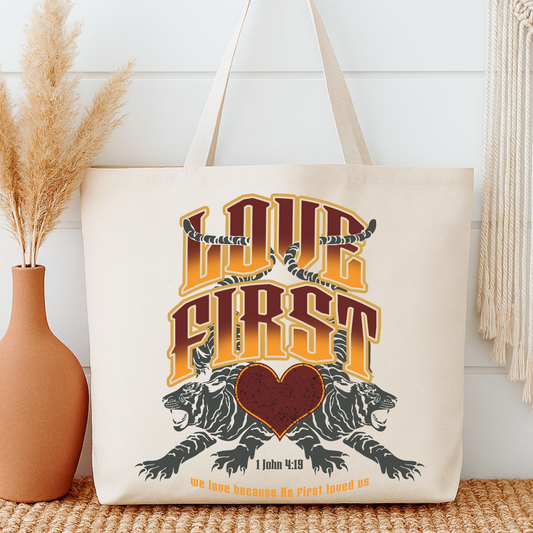 Tote bag with 'Love First' design featuring tigers and a heart, next to a vase and decorative items.