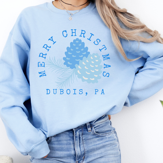 light blue sweatshirt that says Merry Christmas in blue and surrounding blue Christmas pinecones. below you can customized the sweatshirt with your business name, town and state or both