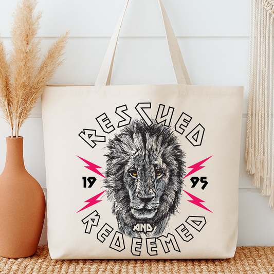 Tote bag with lion graphic and text 'Rescued and Redeemed 1995' on a neutral background