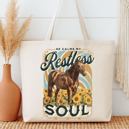 Tote bag with horse and sunflower design, text 'He calms my restless soul', next to a vase and decorative items.