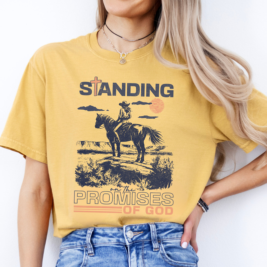 Person wearing a yellow t-shirt with a graphic and text, standing against a plain background.  Standing on the promises of God with a cowgirl on a horse looking over the plains