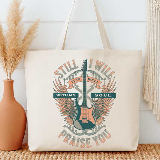 Tote bag with guitar design and text next to a vase on a wooden surface.  Still I will Praise you