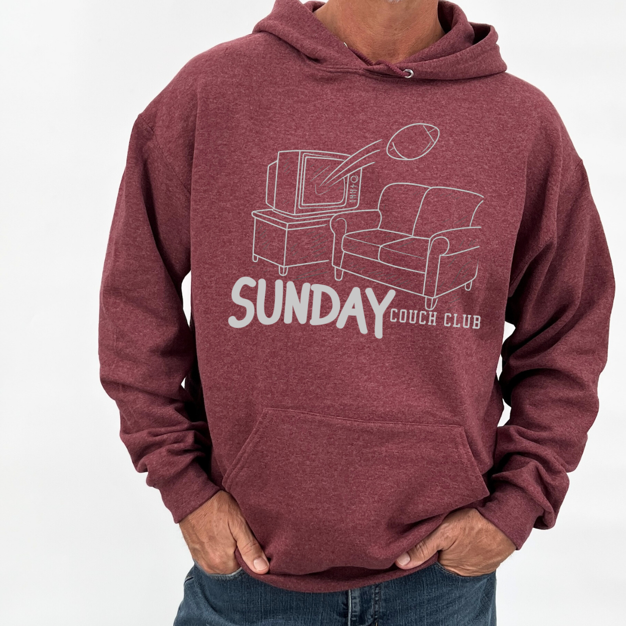 Maroon hoodie with 'Sunday Couch Club' graphic design on a white background.  Graphic is a pencil drawing of a tv and couch with a football coming out of the TV