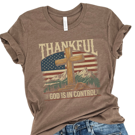 Brown t-shirt with American flag, cross, and mountain graphic on a white background.  Thankful God is in Control