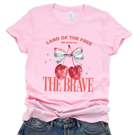 Pink t-shirt with cherry design and text on a white background.  Land of the Free because of the Brave