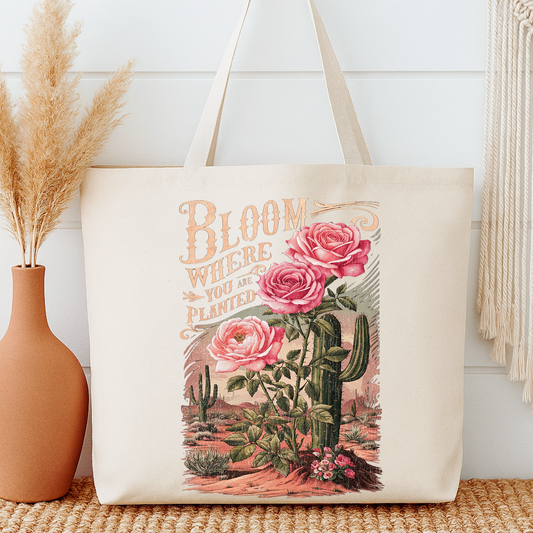 Tote bag with floral and cactus design and 'Bloom Where You Are Planted' text next to a vase.