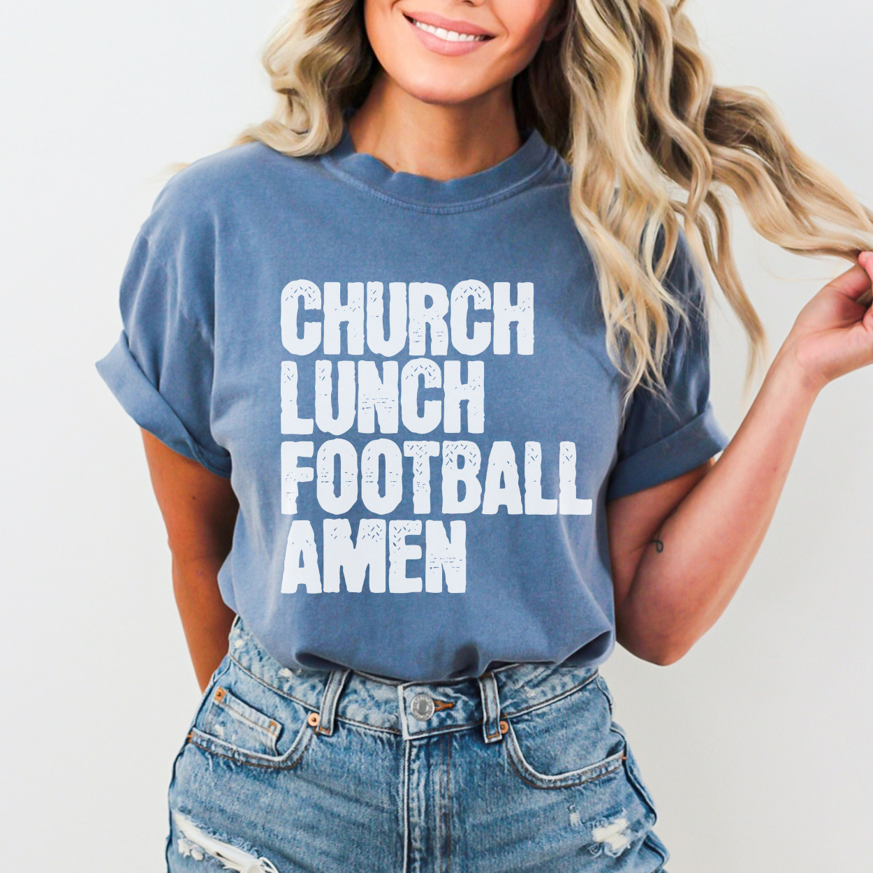 Person wearing a blue t-shirt with 'Church Lunch Football Amen' text on a plain background
