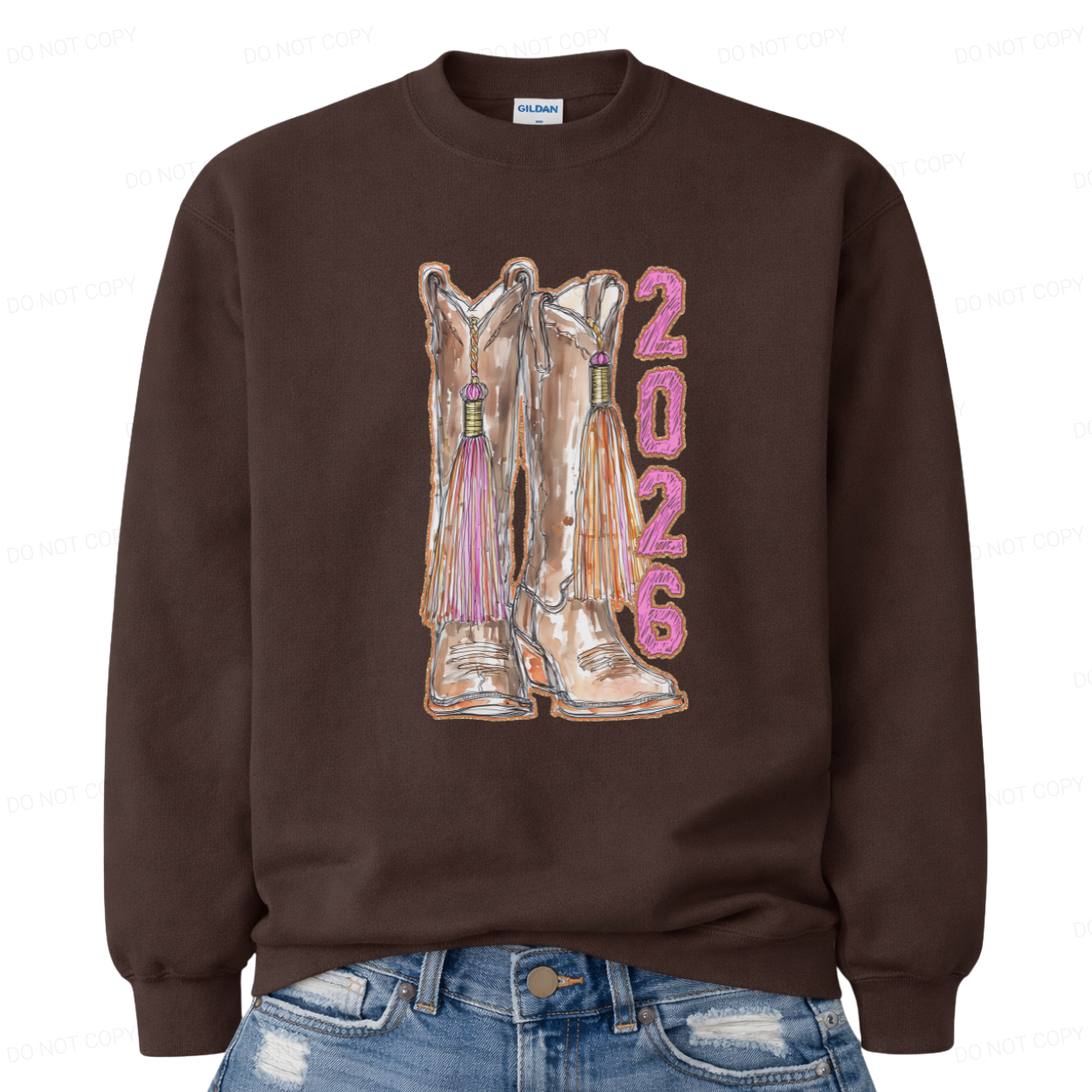 Brown sweatshirt with cowboy boots and '2026' printed on it, worn with blue jeans.