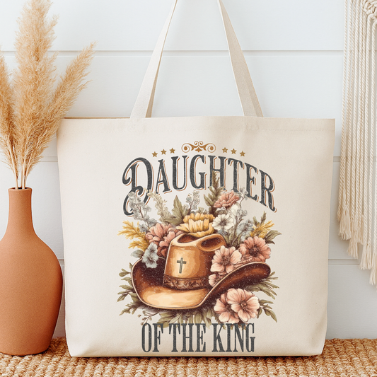 Tote bag with 'Daughter of the King' design featuring a cowboy hat and flowers, placed on a surface with a vase and decorative items.