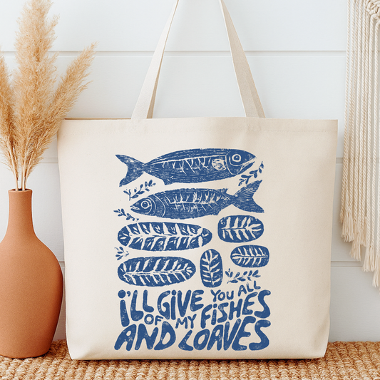 Tote bag with fish design and text next to a vase on a wooden surface.  I'll give you all of my fishes and loaves