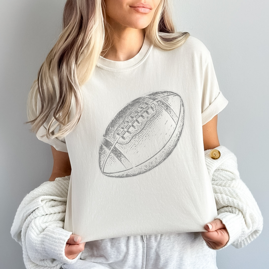 Person wearing a white t-shirt with a football graphic on a plain background