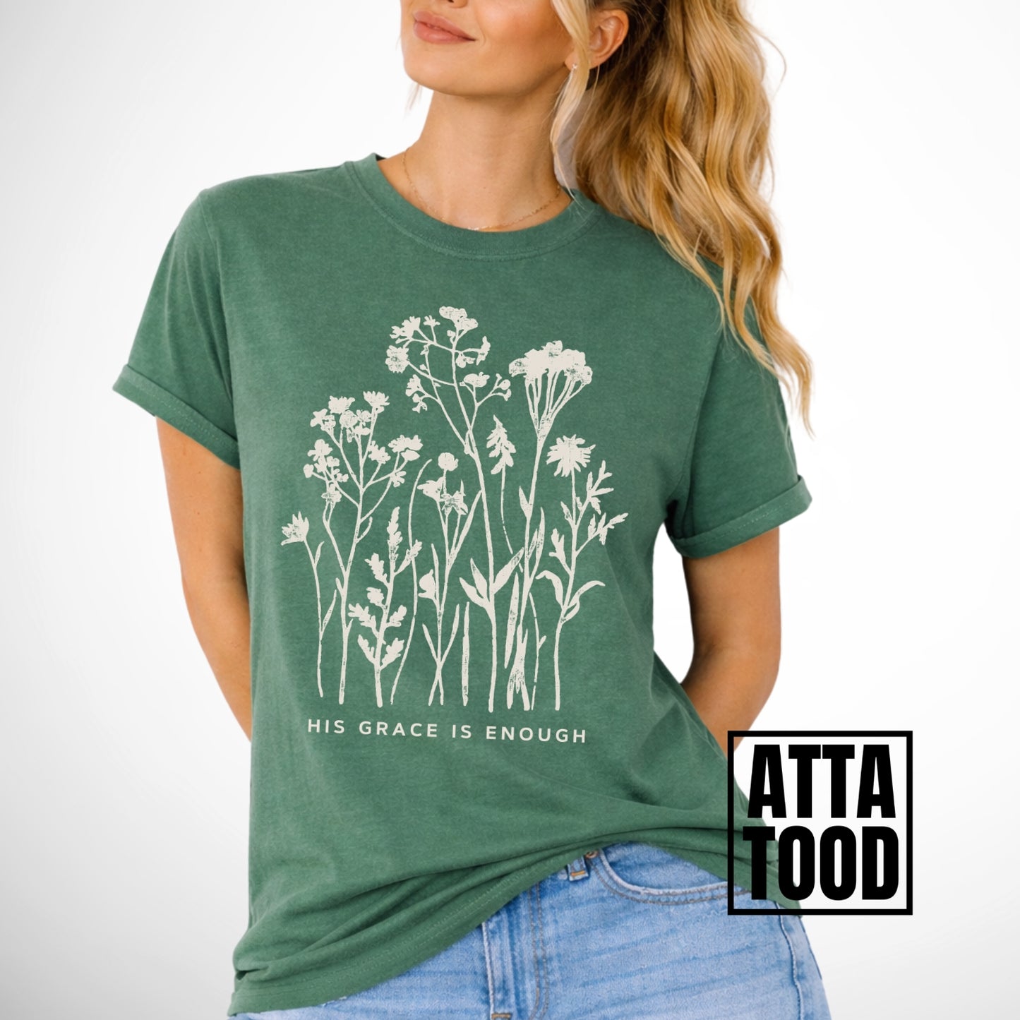 Woman wearing a green t-shirt with floral design and 'His Grace is Enough' text.