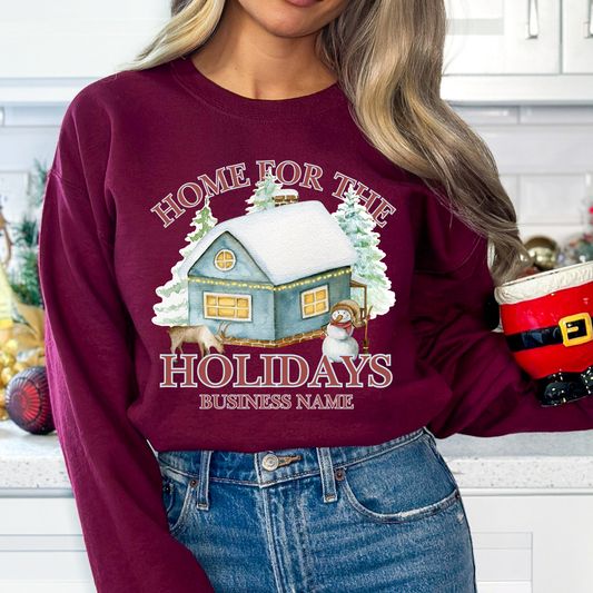 Home for the holidays maroon sweatshirt with graphics of a home in the snow, trees, snowman and a deer. customize with business name, city and state or both