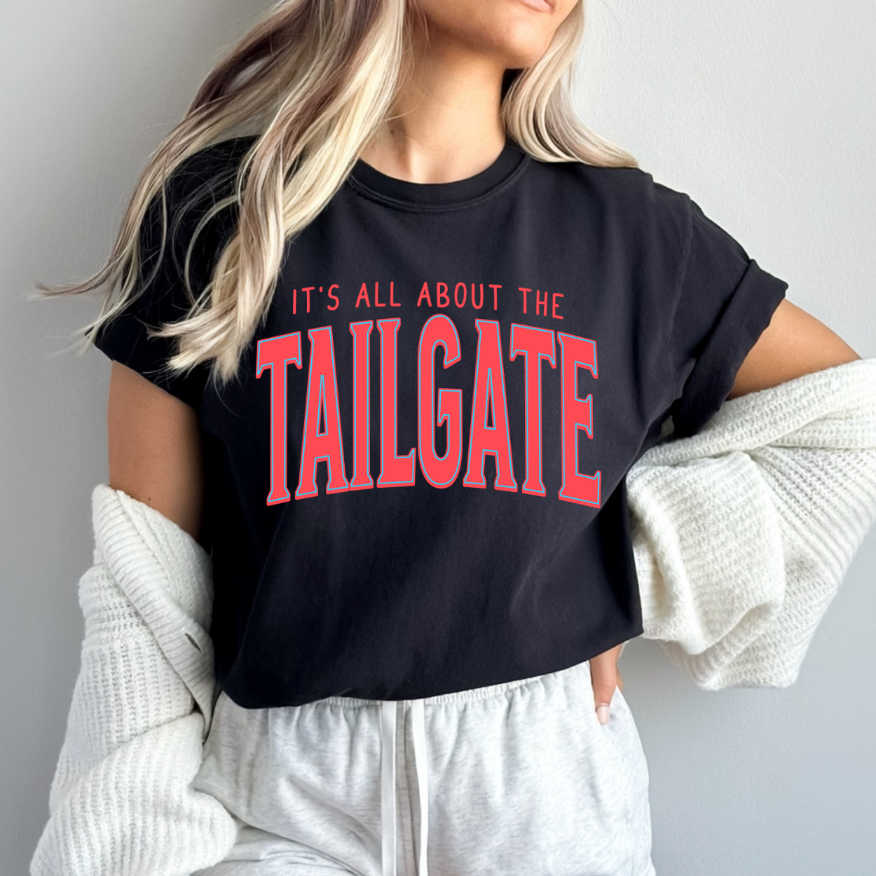 Person wearing a black t-shirt with 'It's All About the Tailgate' text in red.