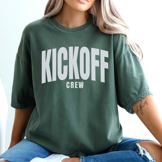 Person wearing a green t-shirt with 'KICKOFF CREW' text on a light background