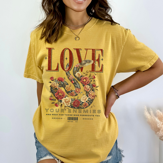 Love your enemies and pray for those who persecute you.  Matthew.  Large floral snake on a mustard yellow t-shirt
