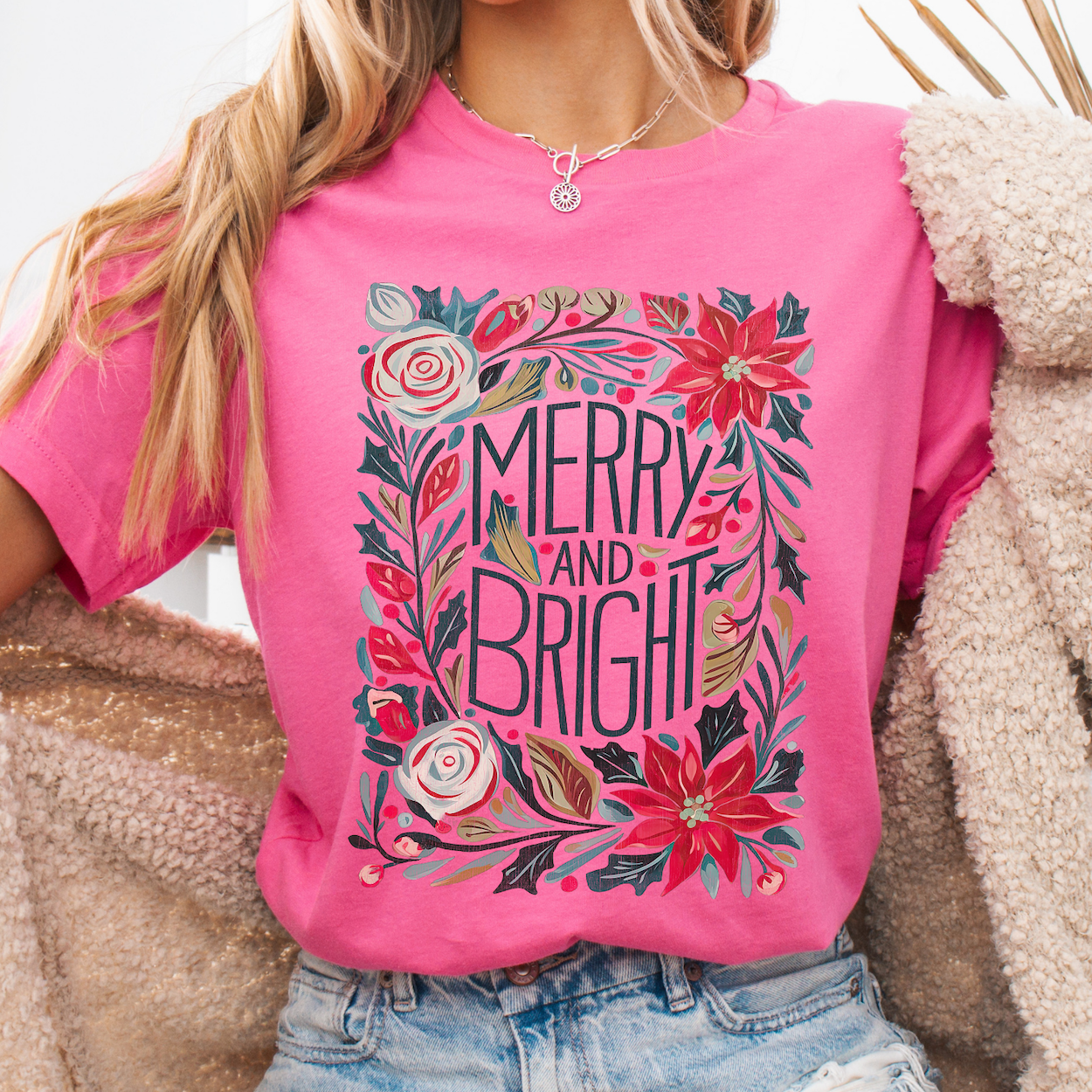 Person wearing a pink t-shirt with floral design and 'Merry and Bright' text.