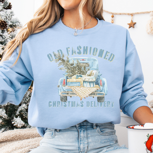 Person wearing a light blue sweatshirt with a Christmas-themed old fashion vintage truck graphic and text.  Shirt says Old fashioned Christmas delivery