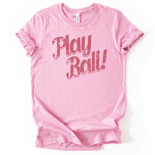 Pink t-shirt with 'Play Ball!' text on a white background