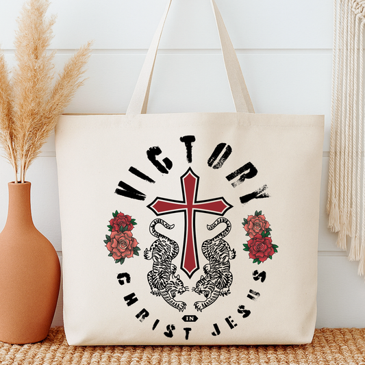 Beige tote bag with a cross, roses, and text design on a white background.  Victory in Christ Jesus