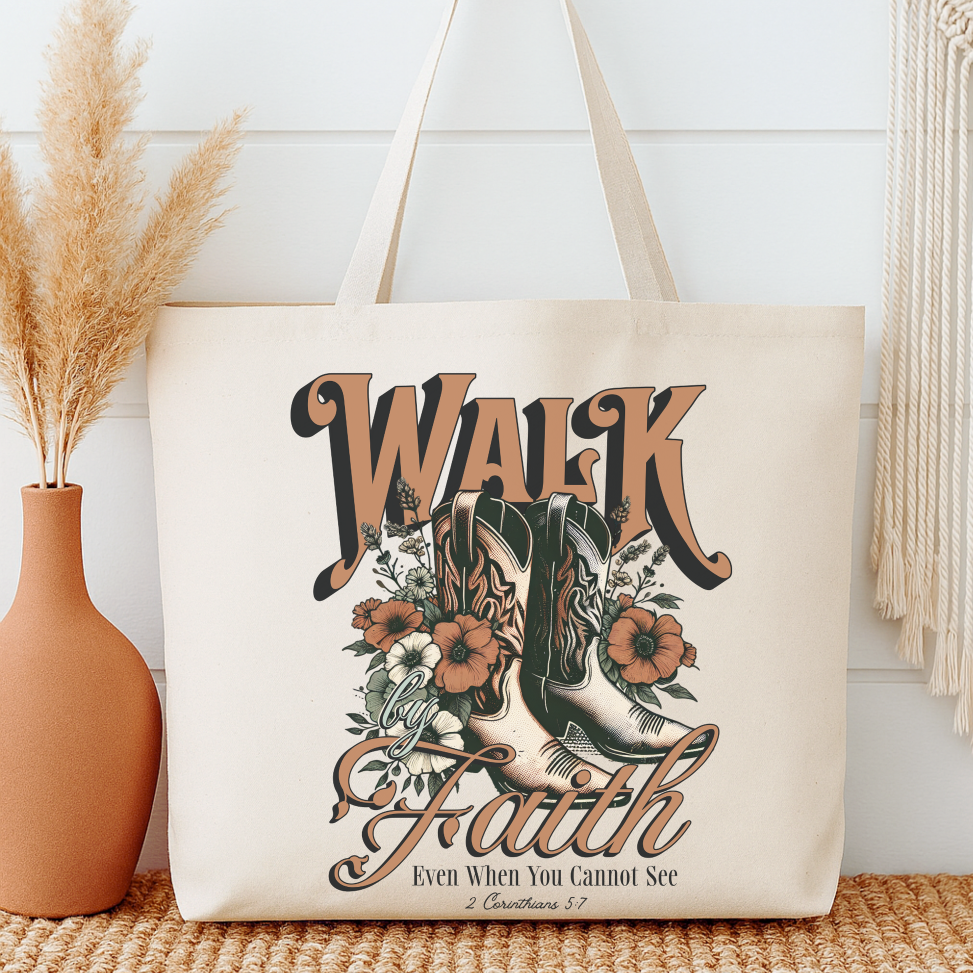 Tote bag with 'Walk by Faith' design featuring boots and flowers, placed on a surface with decorative elements.