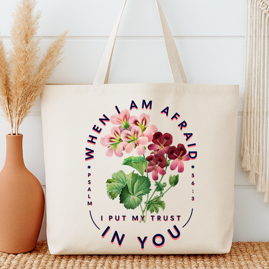 Tote bag with floral design and text next to a vase on a wooden surface.  Text is When I am afraid, I put my trust in you.  Psalm 56:3