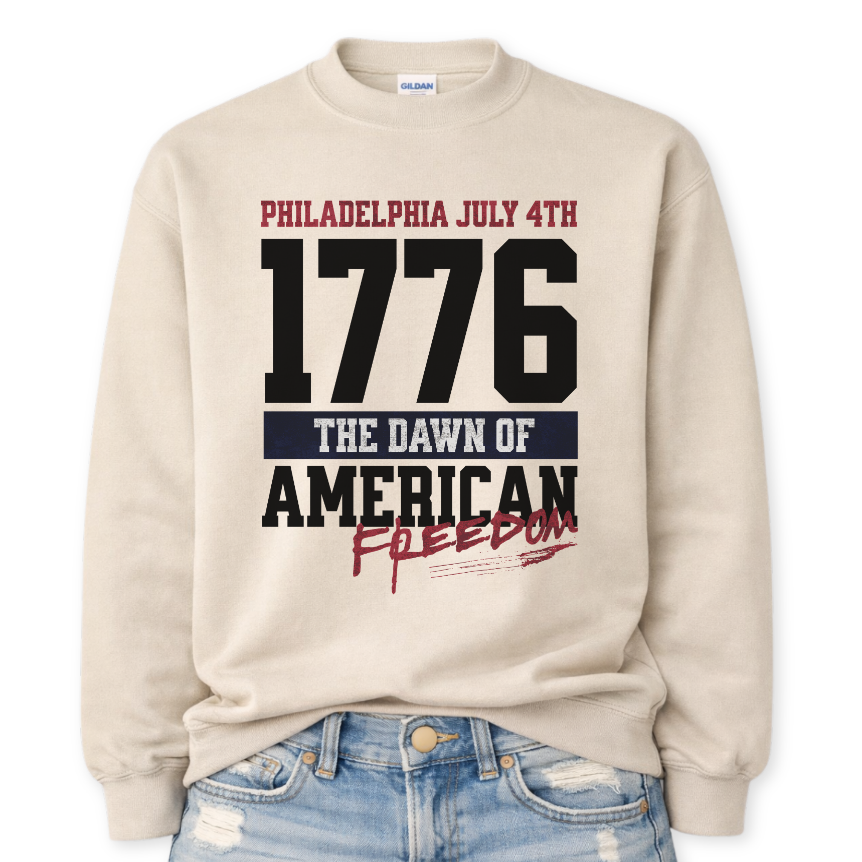 Flat-lay Gildan beige crewneck sweatshirt featuring bold 1776 patriotic graphic with “Philadelphia July 4th” and “American Freedom” text.