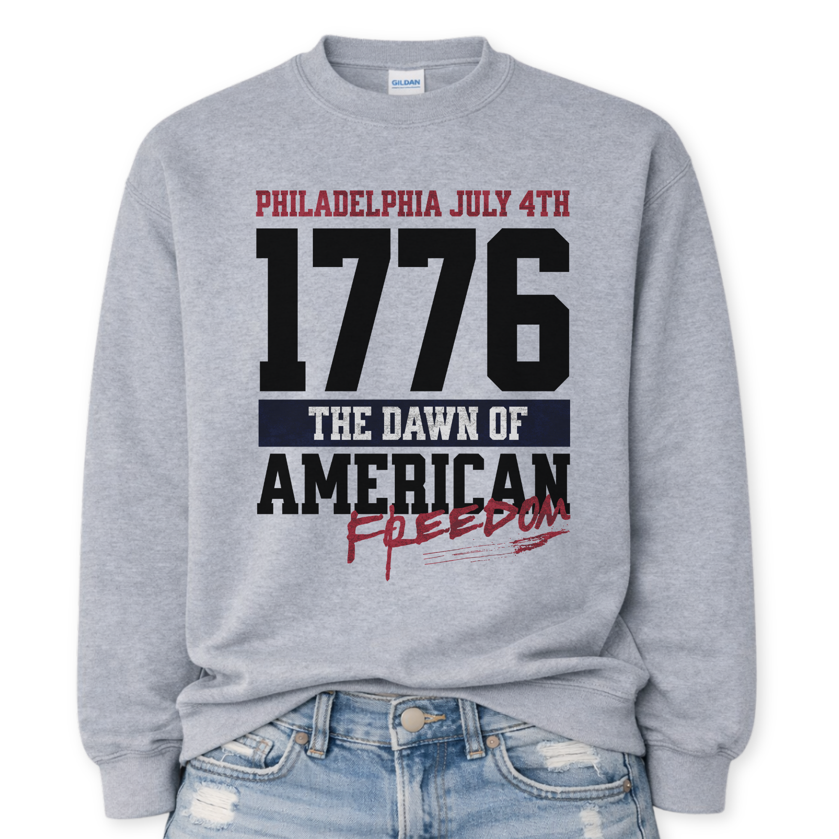 Flat-lay Gildan sport gray crewneck sweatshirt featuring bold 1776 patriotic graphic with “Philadelphia July 4th” and “American Freedom” text.