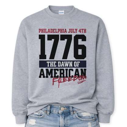 Flat-lay Gildan sport gray crewneck sweatshirt featuring bold 1776 patriotic graphic with “Philadelphia July 4th” and “American Freedom” text.