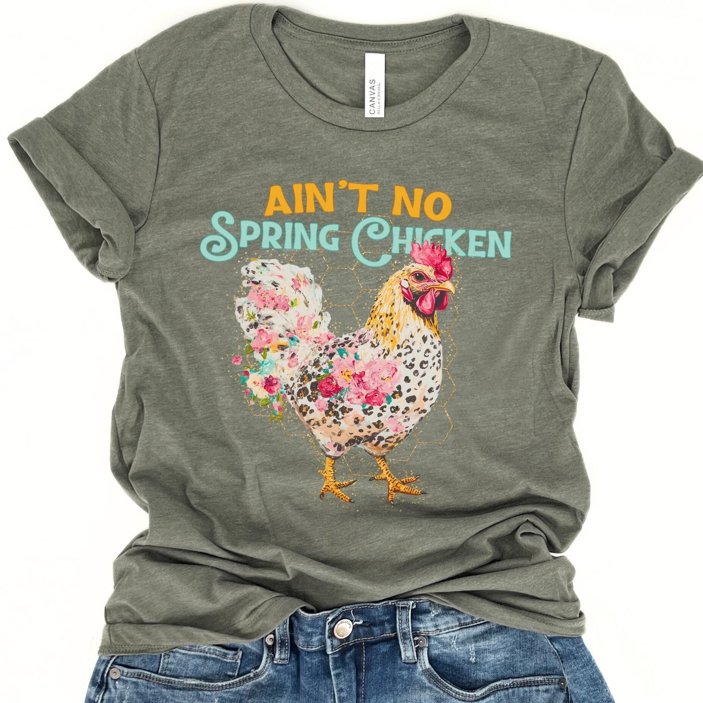 Green t-shirt with floral chicken graphic and text 'Ain't No Spring Chicken' on a white background.