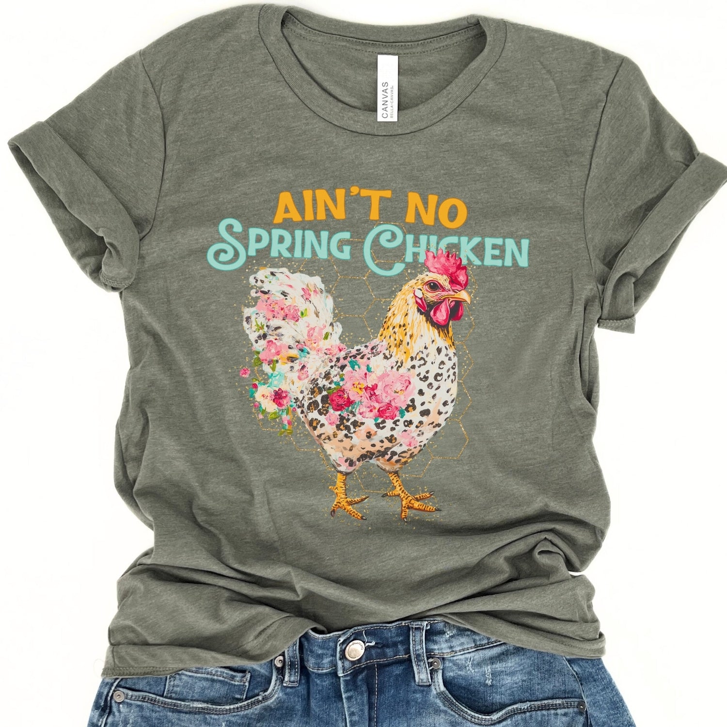 Green t-shirt with floral chicken graphic and text 'Ain't No Spring Chicken' on a white background.