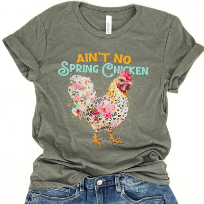 Green t-shirt with floral chicken graphic and text 'Ain't No Spring Chicken' on a white background.
