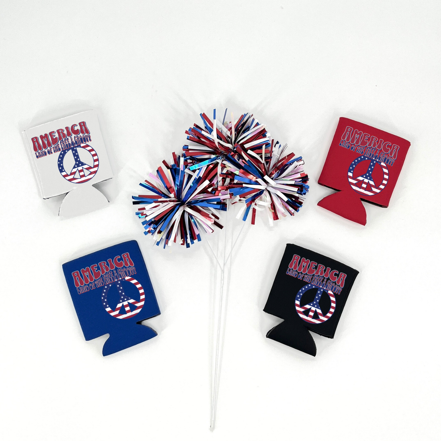 Red, Blue, Black and White collapsible can cooler displayed on a white background with a red, white, and blue metallic pom pom in the foreground. The graphic features retro lettering that reads “America Land of the Free & Groovy” above a peace sign filled with an American flag pattern. Patriotic red, white, and blue graphic printed on the front of the drink sleeve style can cooler.