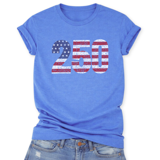 Heather Columbia Blue Bella Canvas t-shirt mockup with rolled sleeves and a front tuck into distressed denim, featuring a large “250” graphic filled with a distressed American flag pattern (white stars and red-and-white stripes).