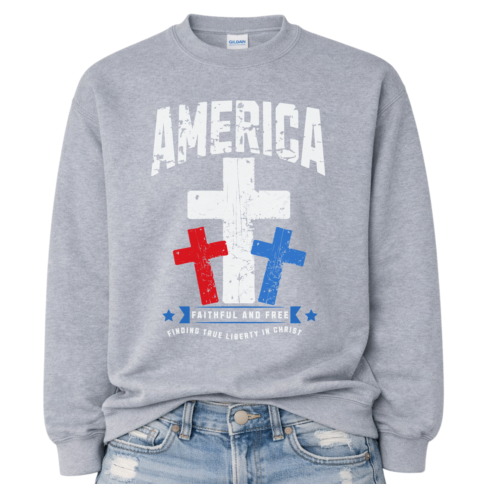 Christian patriotic faith graphic on a gray sweatshirt. The design features a bold distressed “America” arch across the chest with a large central white cross, flanked by red and blue crosses below for a strong USA color story. A banner reading “Faithful and Free” anchors the design, with smaller text noting “Finding True Liberty in Christ,” blending faith-forward messaging with classic Fourth of July patriotic style.